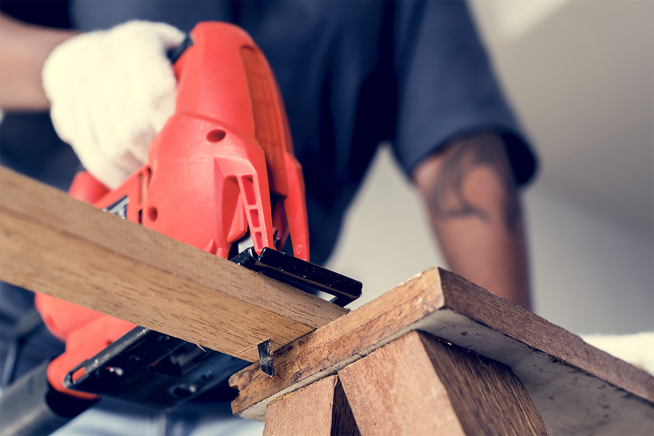 handyman cutting a board with a jigsaw for hired project