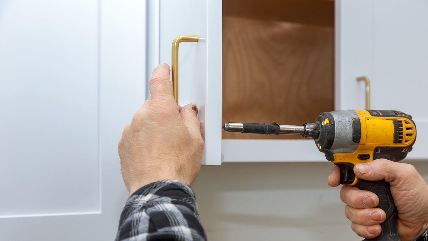 man installing new hardware on kitchen cabinets