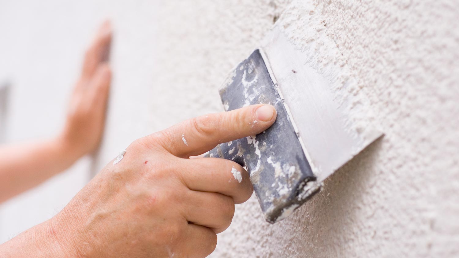 A worker repairing stucco siding